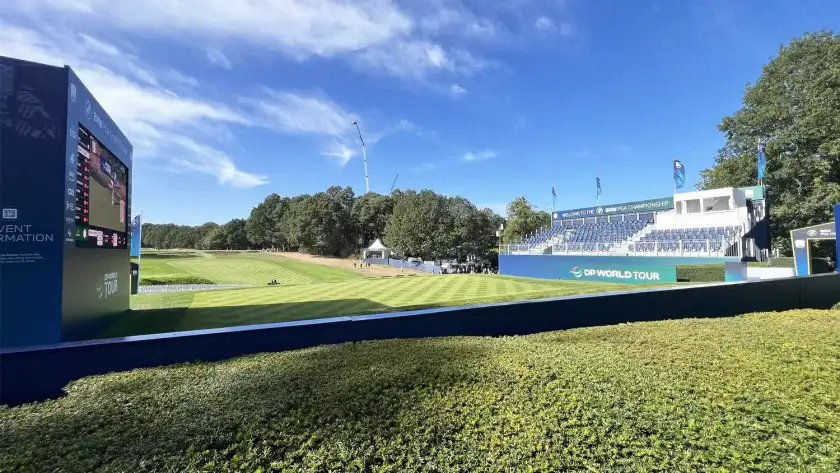 Golf tournament grandstand and leaderboard beside a green fairway, one of the sporting events we arrange tickets for